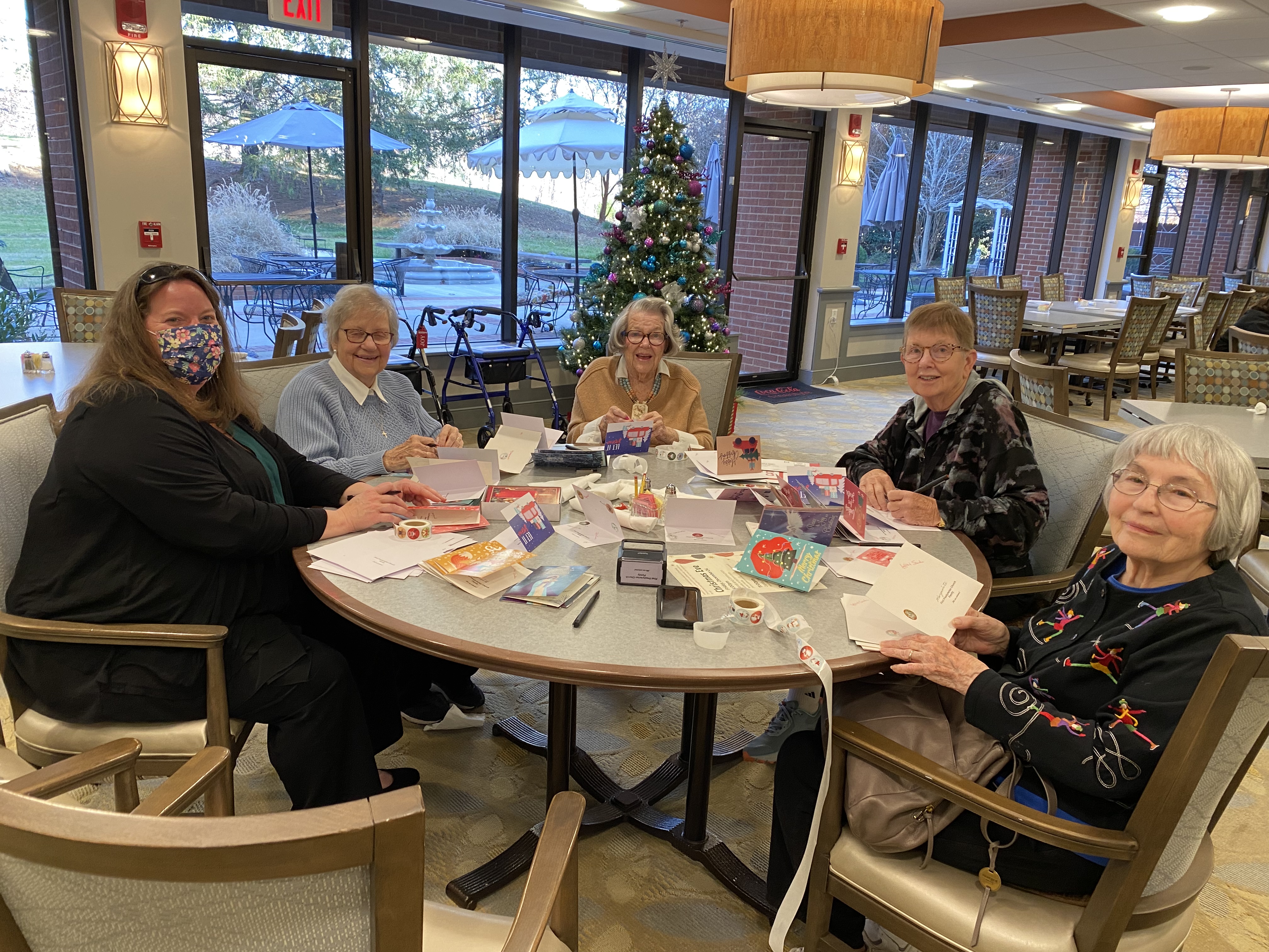 group of elderly, senior adults around a table signing cards for others