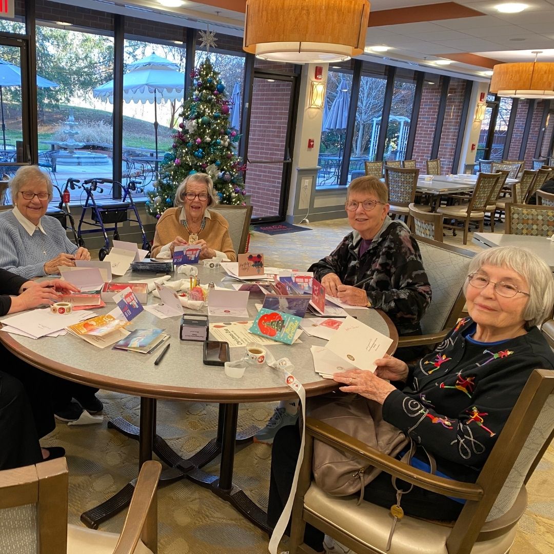 group of elderly women at a table signing cards together