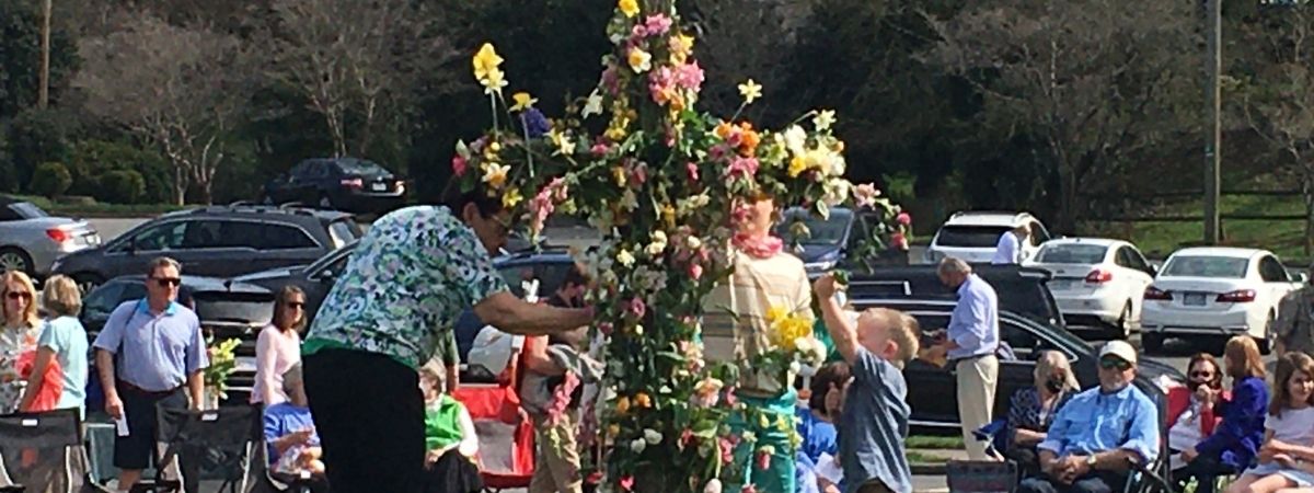 people gathered around a cross putting flowers it to celebrate Easter