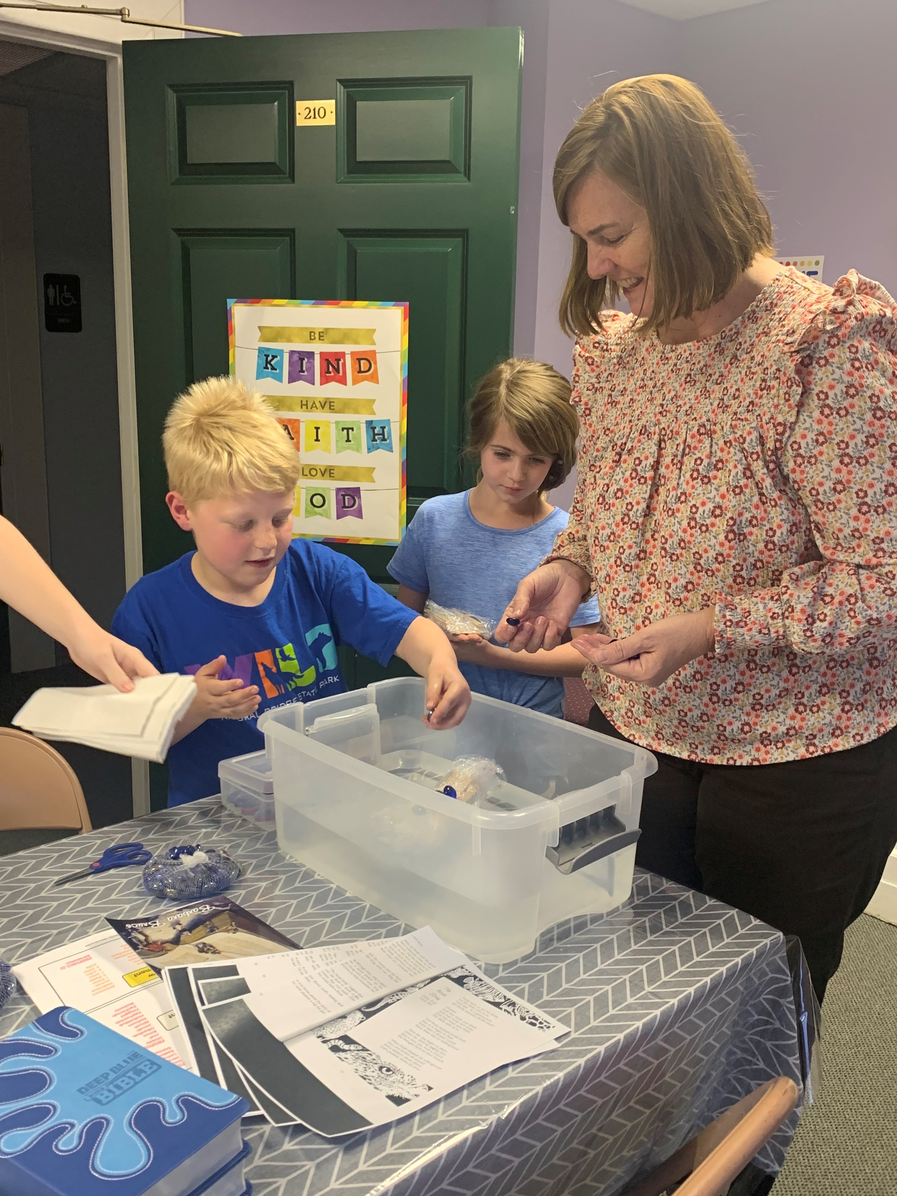 lady teaching two children with a project