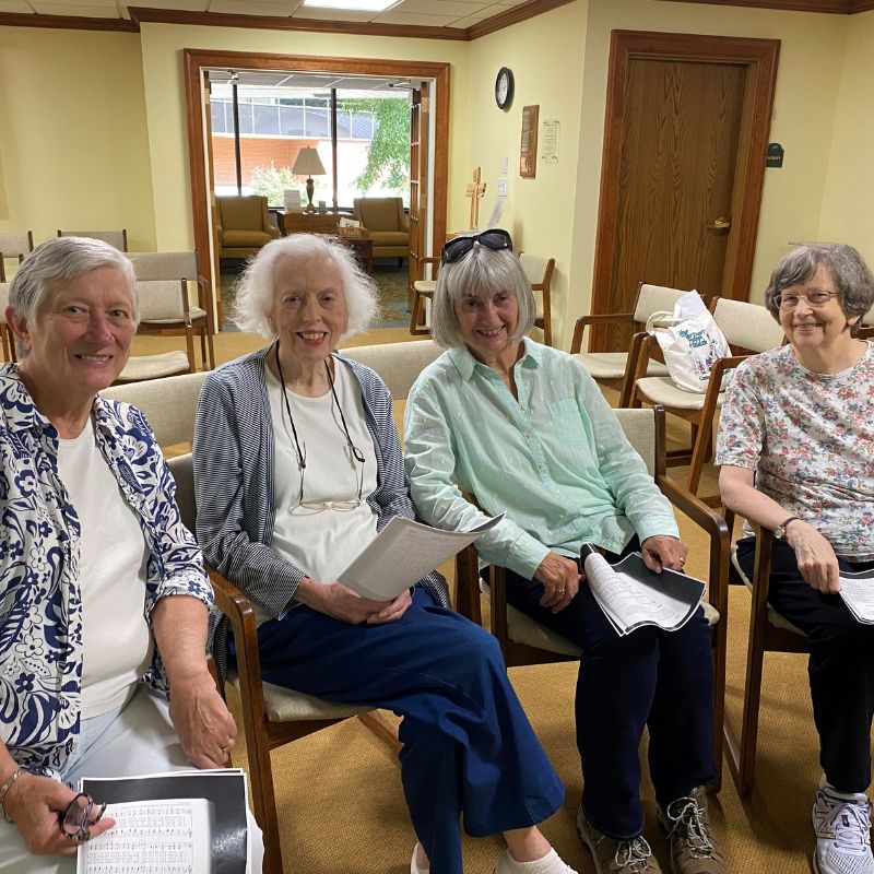 group of elderly women at a table signing cards together