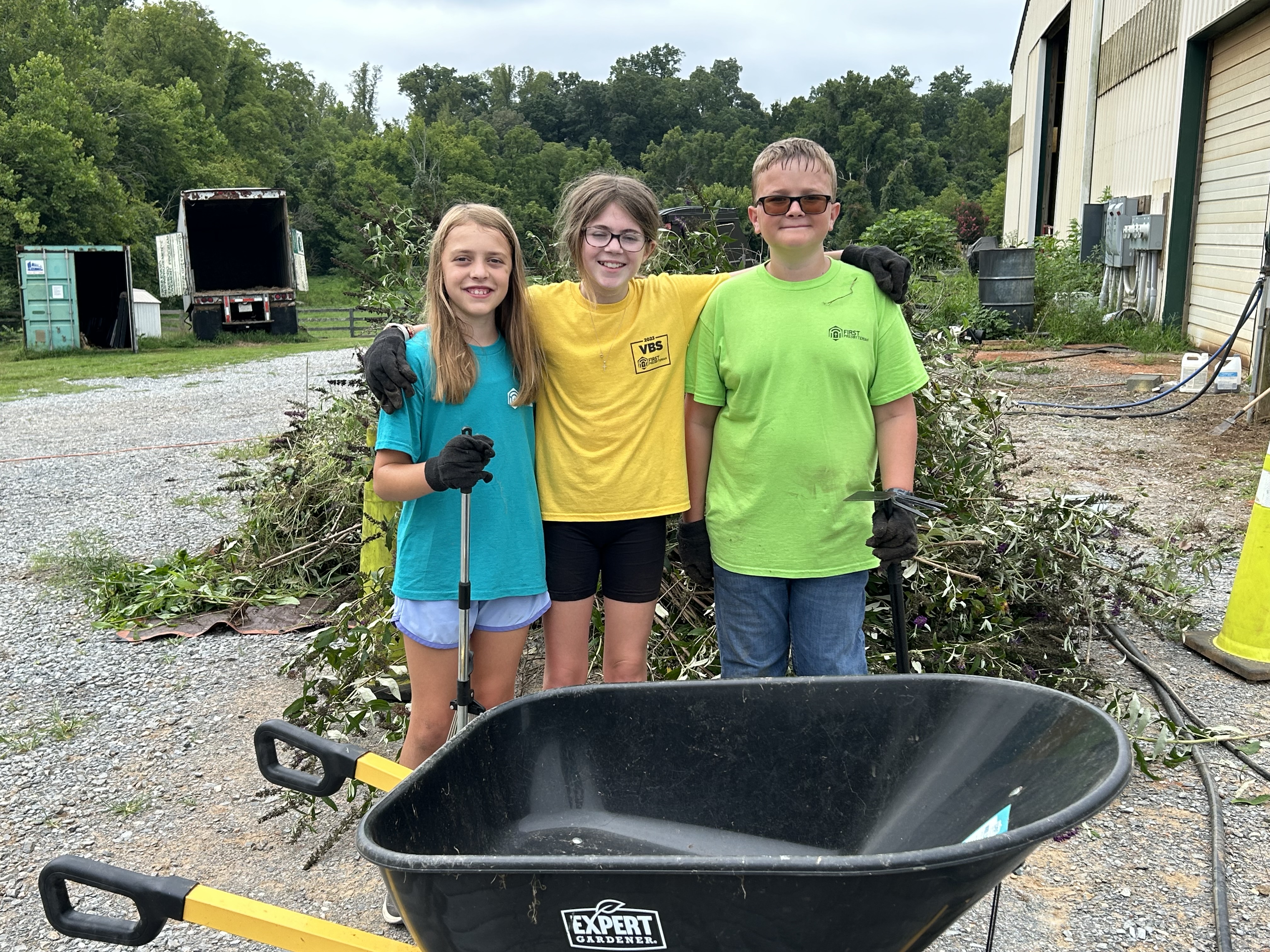 Kid volunteers with a wheelbarrow helping with lawn work